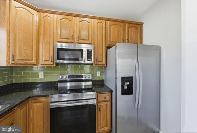 a kitchen with stainless steel appliances granite countertop a refrigerator and a sink