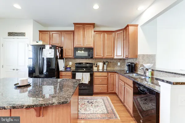 a kitchen with stainless steel appliances granite countertop a sink refrigerator and cabinets