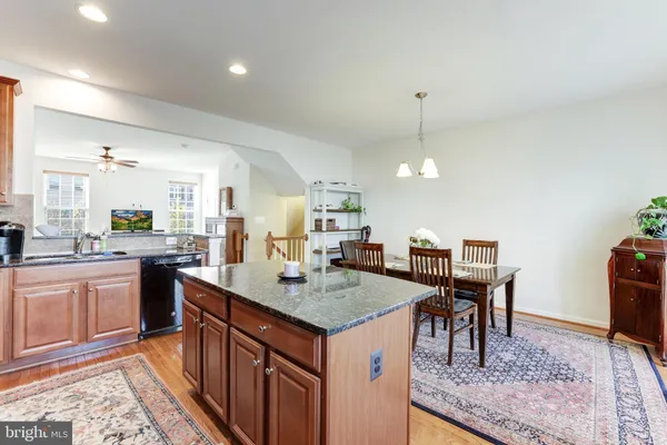 a kitchen with a stove a sink dishwasher and a dining table with wooden floor