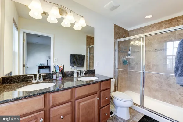 a bathroom with a granite countertop double vanity sink mirror and toilet