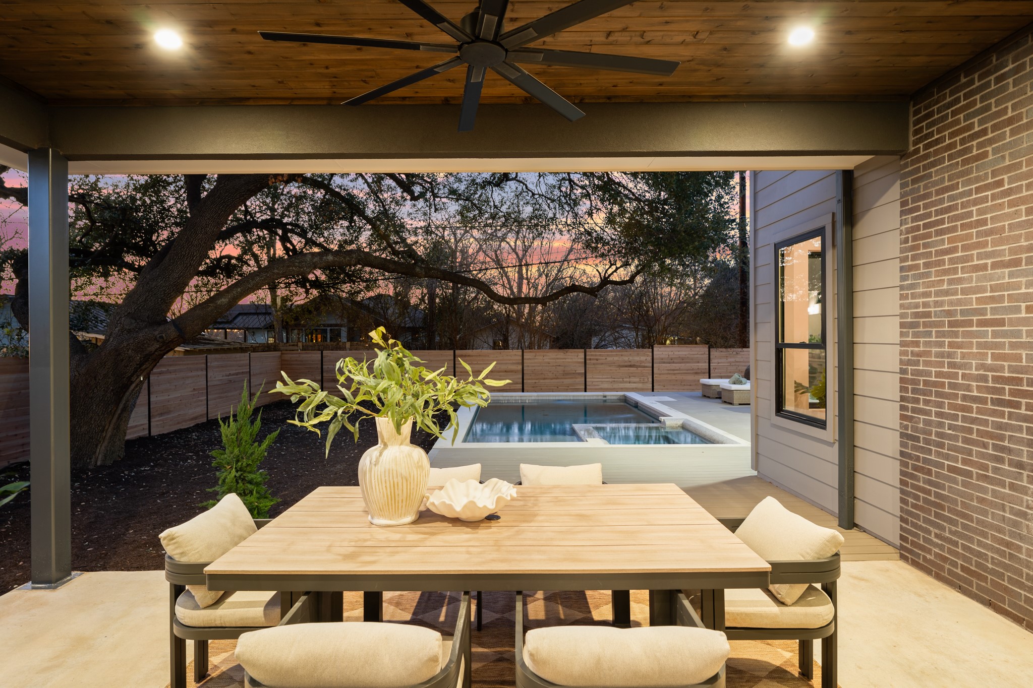 7706 Rutgers Avenue Austin, TX 78757 - Photo 23 of 35 Fenced backyard with ceiling fan, a patio area, outdoor dining space, an outdoor hot tub, and a swimming pool