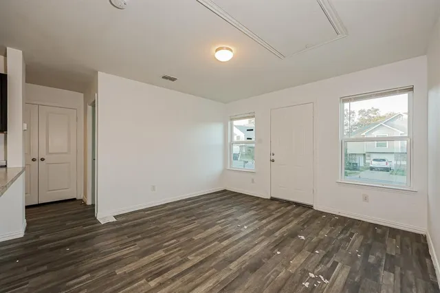an empty room with wooden floor and windows