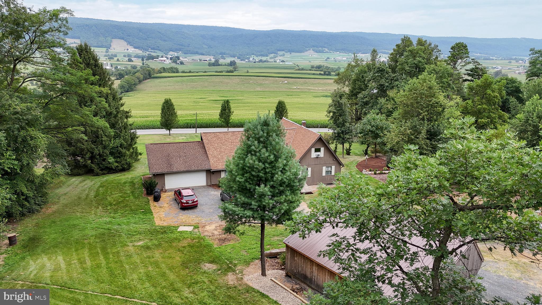 an aerial view of residential house with outdoor space and trees all around