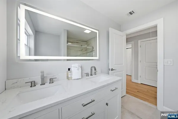 a bathroom with double vanity sink a mirror and a bathtub