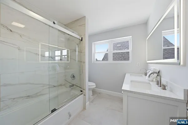 a bathroom with a granite countertop sink a toilet and shower