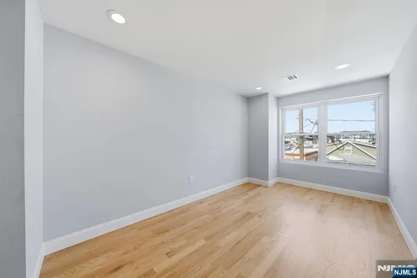 an empty room with wooden floor and window