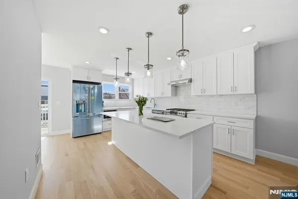 a kitchen with stainless steel appliances white cabinets a sink a stove a refrigerator and island