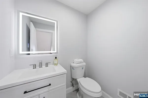 a bathroom with a toilet sink vanity and mirror