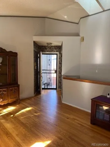 a view of a livingroom with wooden floor and a refrigerator