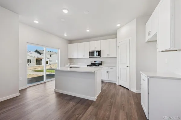 a kitchen with white cabinets and wooden floor