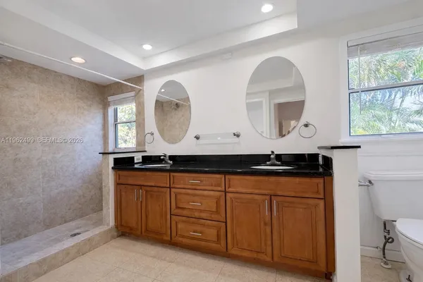 a bathroom with a granite countertop sink a toilet and a shower
