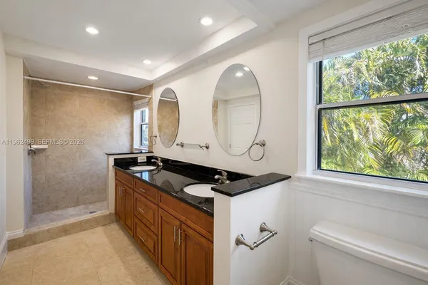a bathroom with a granite countertop sink a mirror and shower