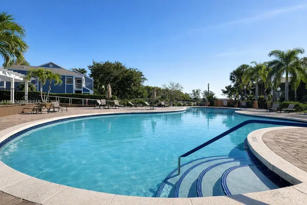 a swimming pool with outdoor seating and palm tree
