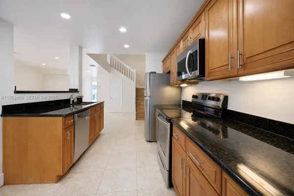 a kitchen with stainless steel appliances granite countertop a sink a stove and a refrigerator