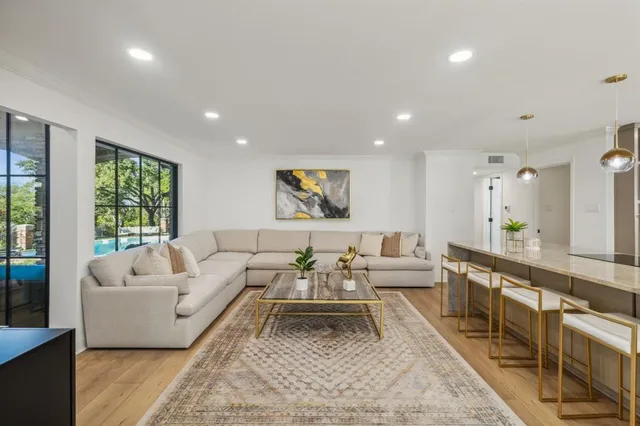 a living room with furniture two large window and a wooden floor