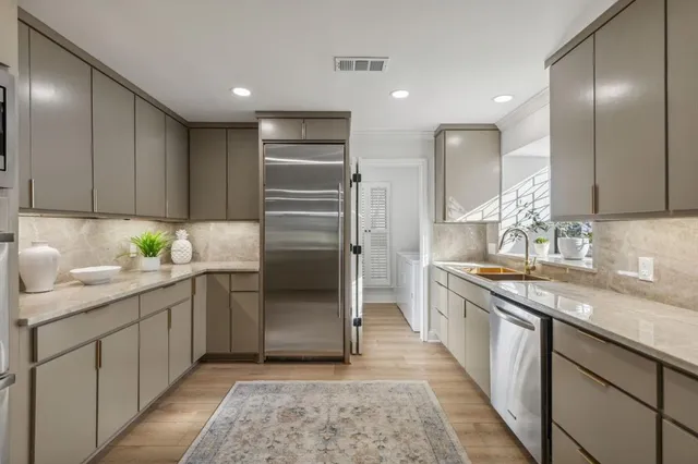 a kitchen with stainless steel appliances granite countertop a sink and a refrigerator