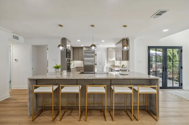 a dining hall with stainless steel appliances granite countertop a table and chairs in it