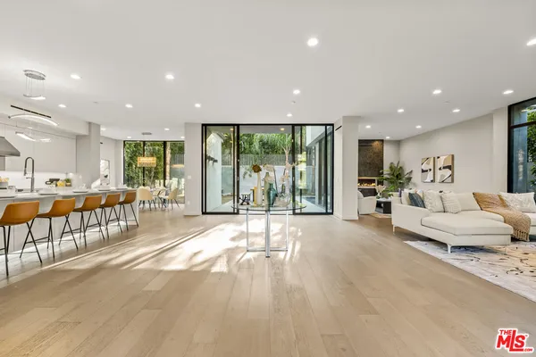 a large living room with stainless steel appliances furniture large windows and a rug