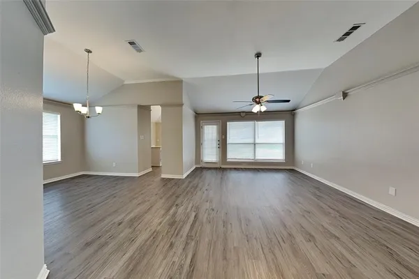 an empty room with wooden floor ceiling fan and windows