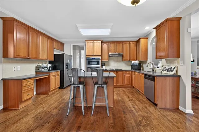 a kitchen with stainless steel appliances granite countertop a sink a stove and a wooden floors