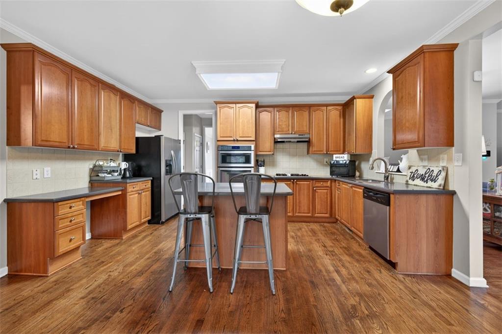 2641 Hillgrove Drive Dacula, GA 30019 - Photo 16 of 57 a kitchen with stainless steel appliances wooden floors and wooden cabinets