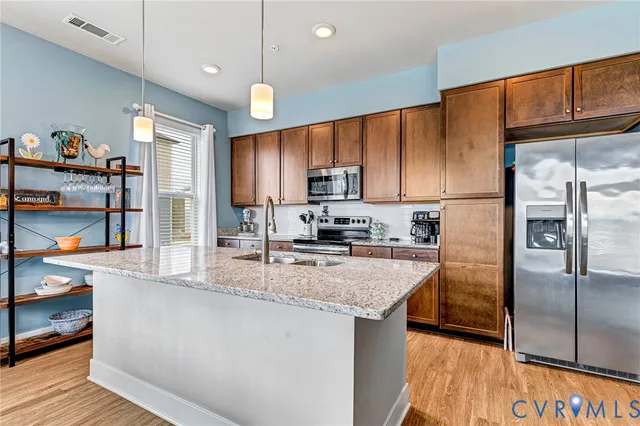 a kitchen with stainless steel appliances granite countertop a refrigerator a stove and a sink