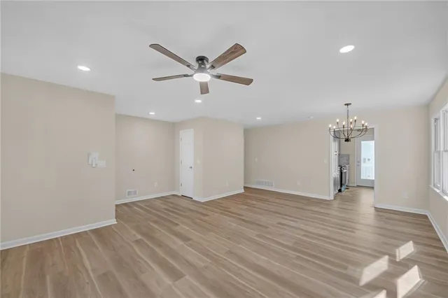 an empty room with wooden floor and ceiling fan