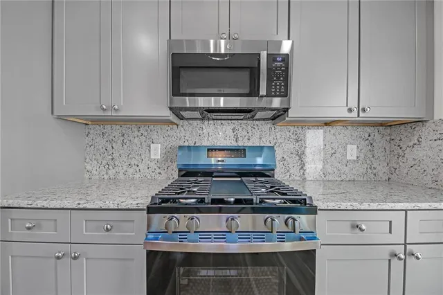 a kitchen with stainless steel appliances granite countertop white cabinets stove top oven and microwave