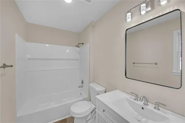 a bathroom with a bathtub shower sink vanity mirror and toilet