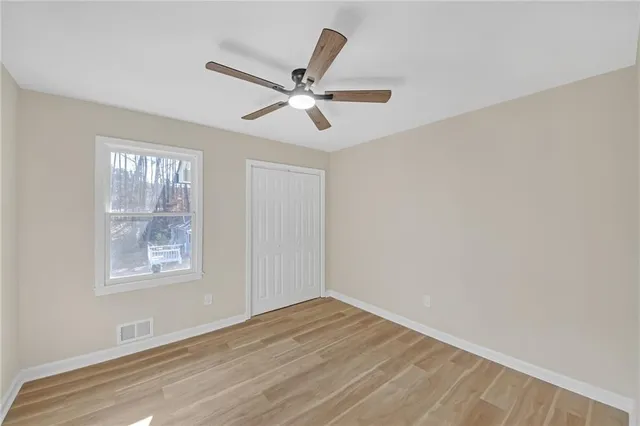 a view of an empty room with wooden floor and a window
