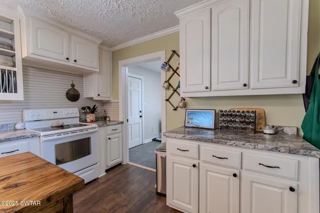 a kitchen with stainless steel appliances granite countertop a stove a sink and white cabinets