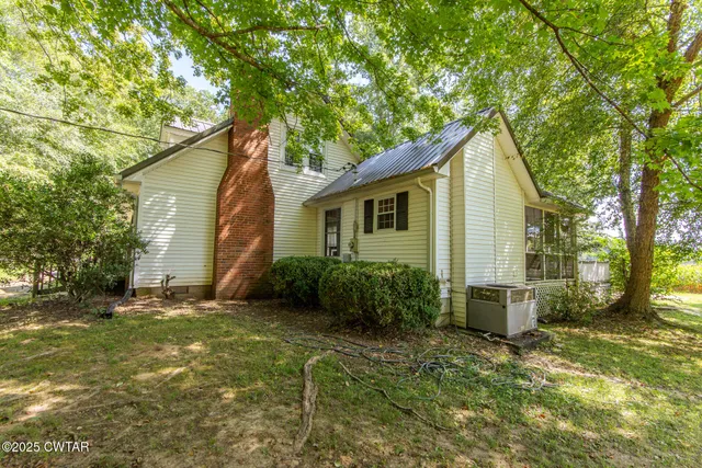 a backyard of a house with plants and large tree