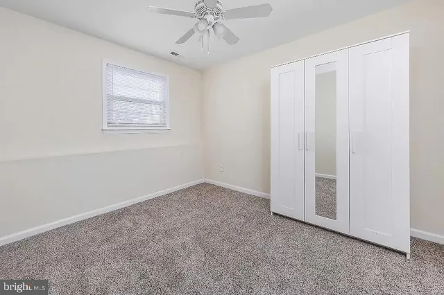 an empty room with a ceiling fan and a window