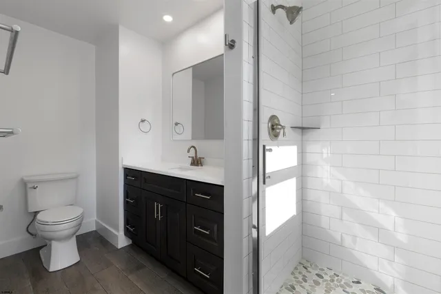 a bathroom with a granite countertop sink a toilet and a mirror