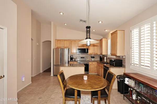 a kitchen with stainless steel appliances kitchen island granite countertop a table chairs stove and refrigerator