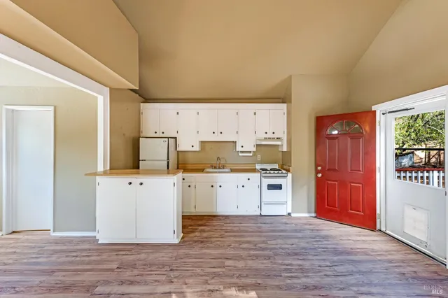 a living room with stainless steel appliances furniture a rug and a kitchen view