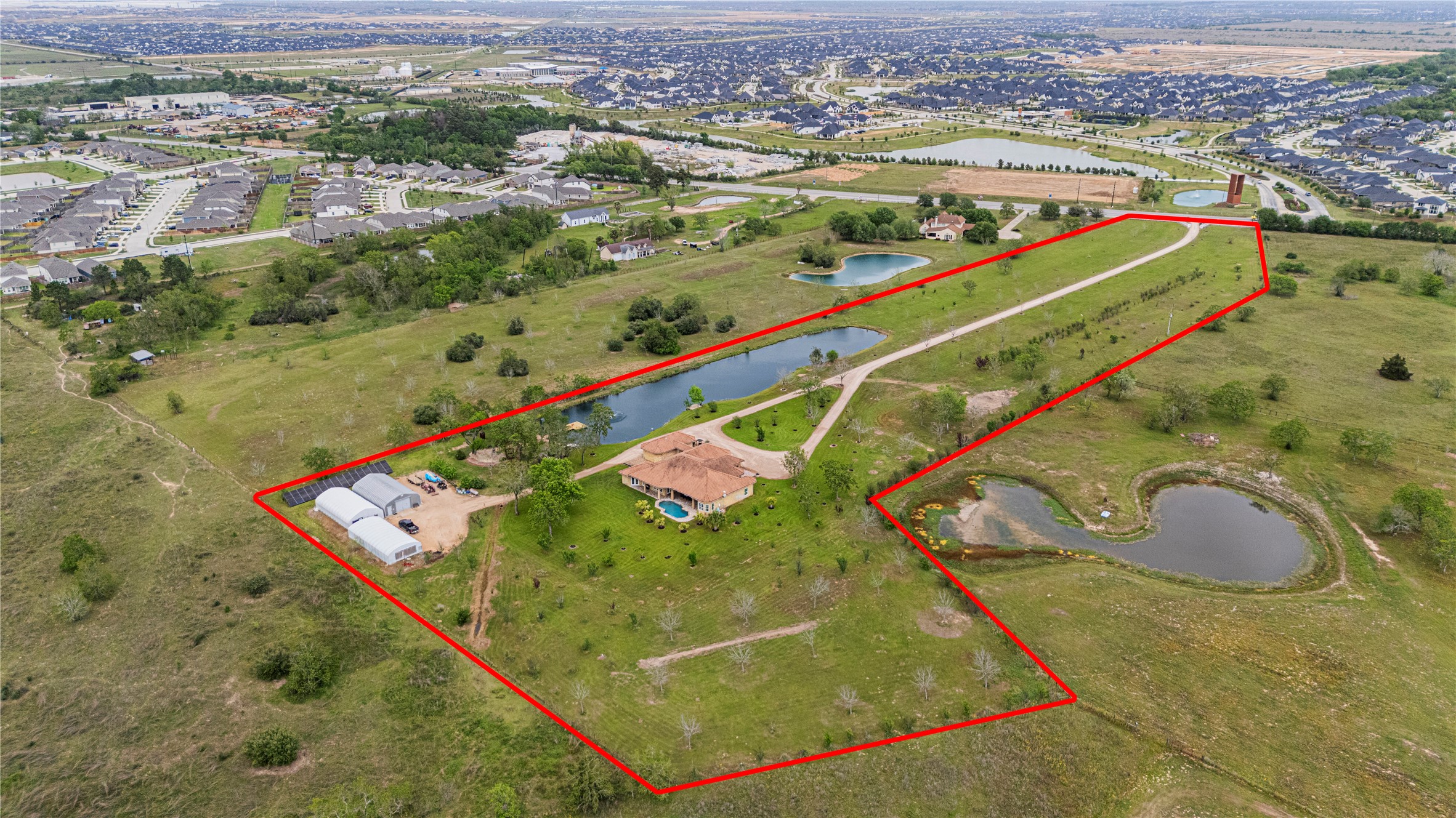 6306 Farm To Market 359 Fulshear, TX 77441 - Photo 6 of 44 This breathtaking aerial perspective reveals the immense scale of the 12.6-acre property, showcasing the 1,500 sq. ft. barn, stocked fishing pond with pier, and lush pecan and fruit trees with convenient access to FM 359.