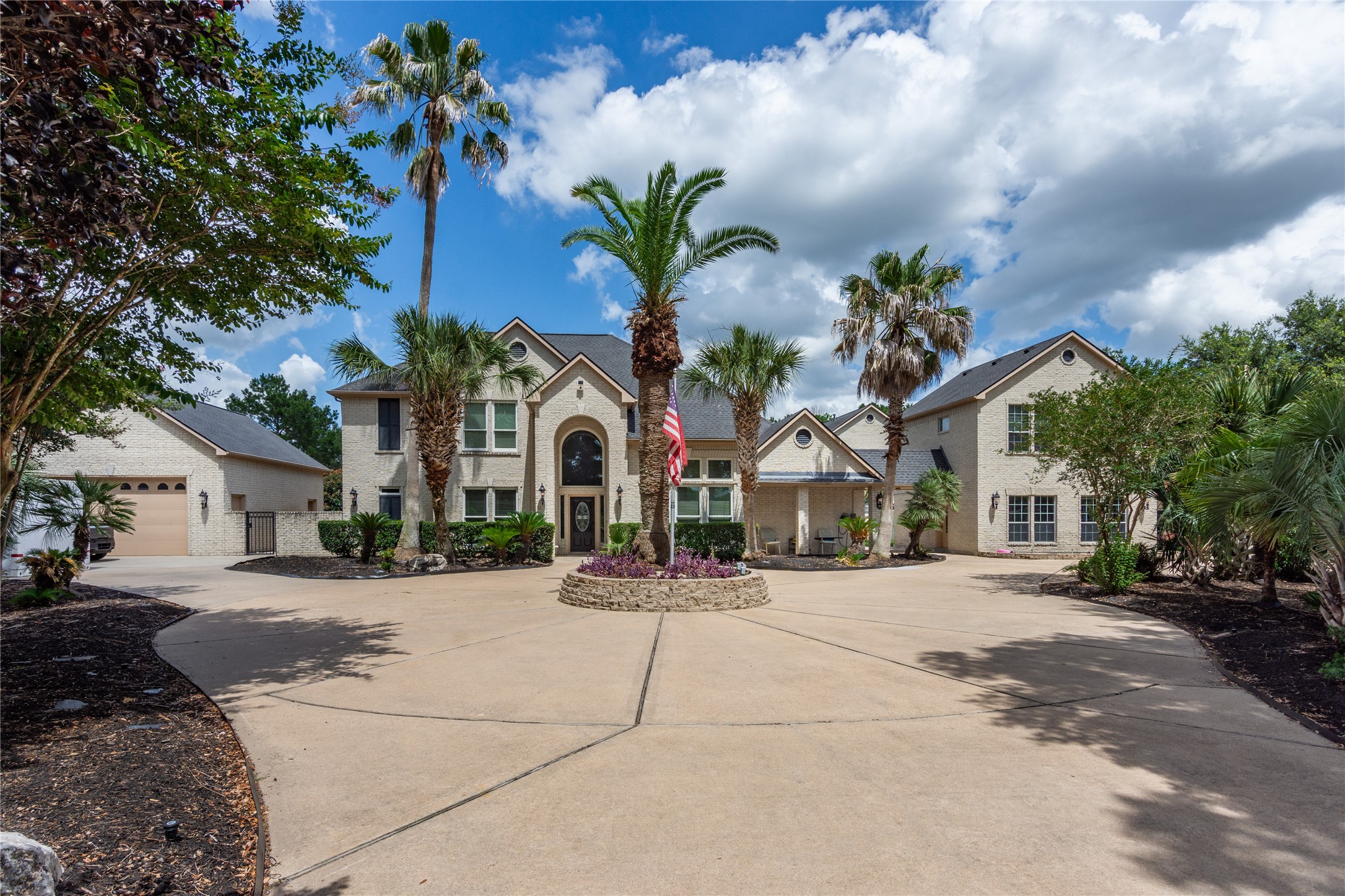 13914 Skinner Road Cypress, TX 77429 - Photo 2 of 50 Grand front approach showcasing the white brick main residence, sweeping circular driveway, mature palm trees, manicured landscaping, and multiple connected living spaces.