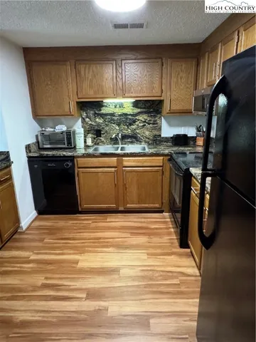 a kitchen with stainless steel appliances granite countertop a stove a sink dishwasher and a refrigerator with wooden cabinets