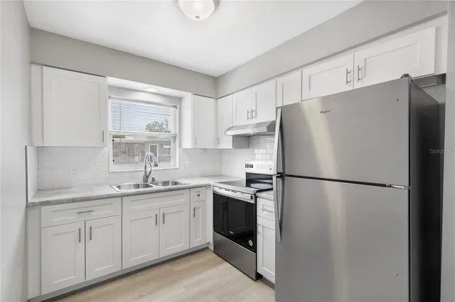 a white refrigerator freezer sitting inside of a kitchen with stainless steel appliances granite countertop cabinets and a refrigerator