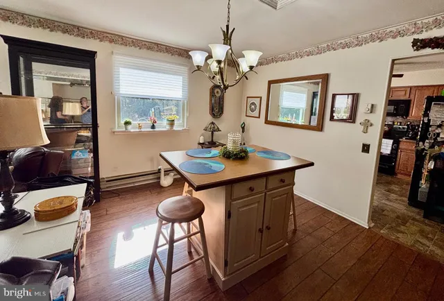 a dining room with wooden floor a chandelier a wooden table and chairs