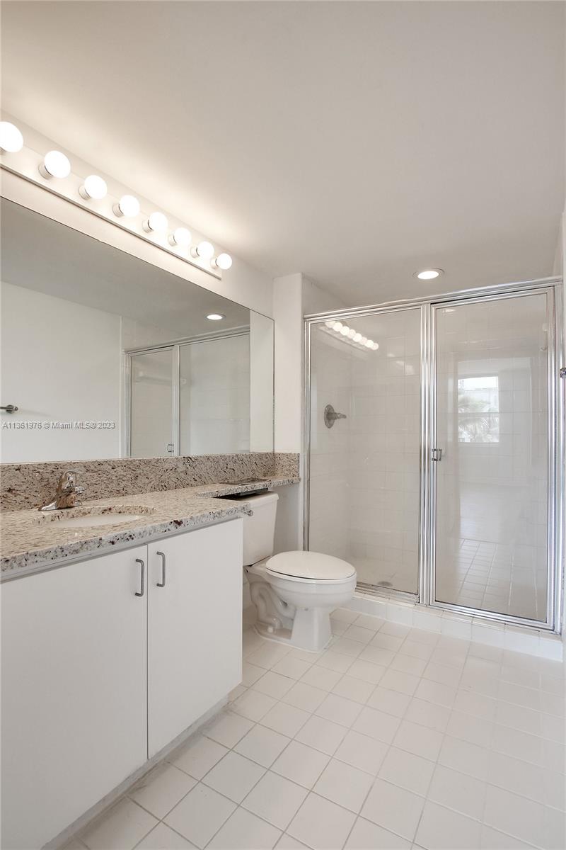 1111 Brickell Bay Drive, Unit 1102 Miami, FL 33131 - Photo 38 of 72 a bathroom with a granite countertop sink a toilet a mirror and a shower