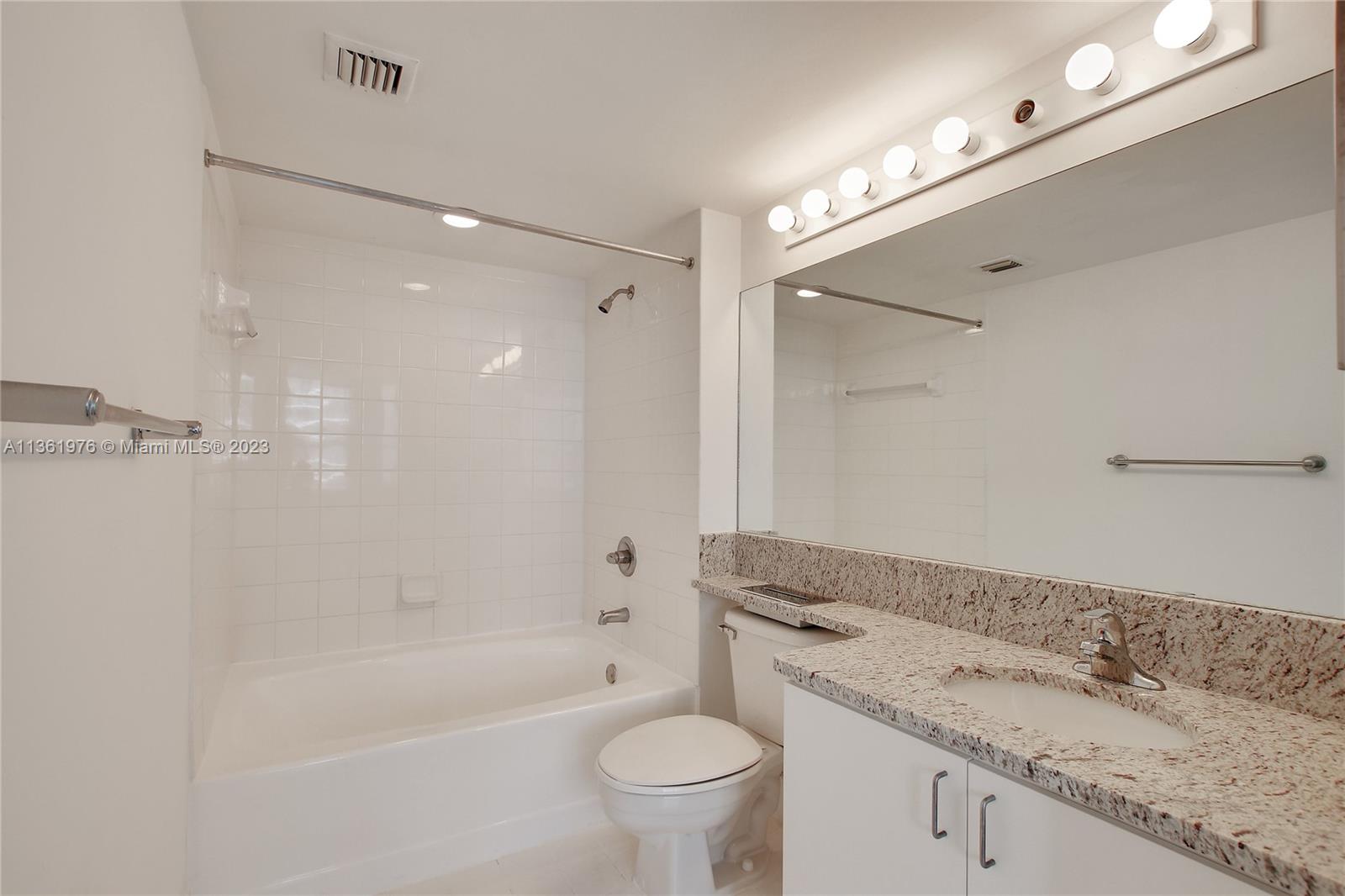 1111 Brickell Bay Drive, Unit 1102 Miami, FL 33131 - Photo 39 of 72 a bathroom with a granite countertop sink a toilet and bathtub