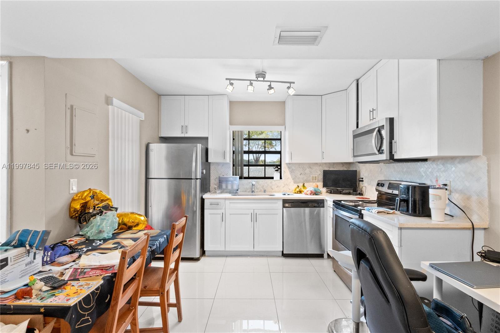 6211 Southwest 138th Court, Unit B Miami, FL 33183 - Photo 4 of 24 a kitchen with stainless steel appliances granite countertop a stove refrigerator a sink dishwasher a dining table and chairs with wooden floor