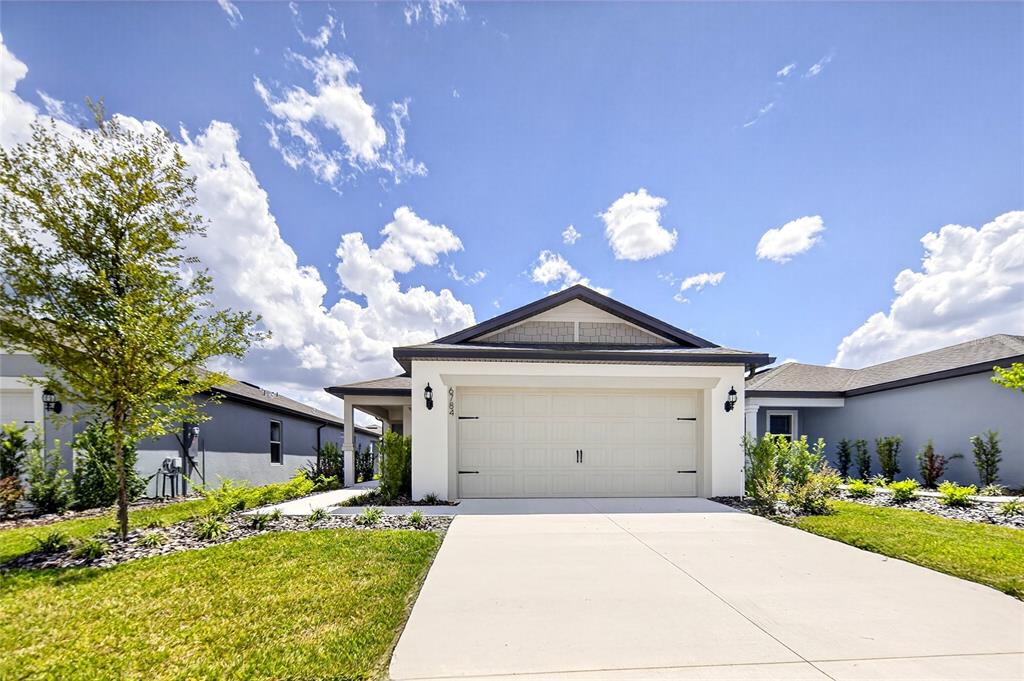 6784 Southwest 90th Loop Ocala, FL 34476 - Photo 1 of 11 a front view of a house with a yard and garage