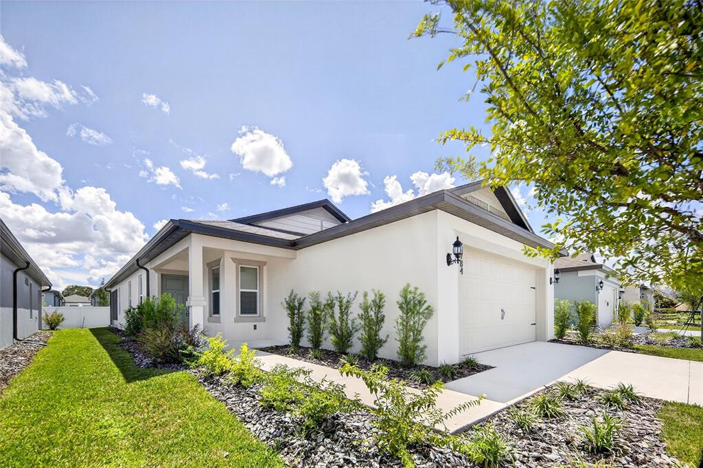 6784 Southwest 90th Loop Ocala, FL 34476 - Photo 3 of 11 a front view of a house with a yard and a garden