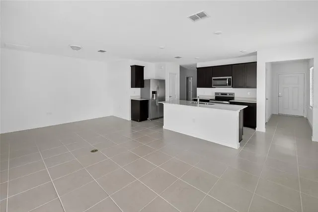 a kitchen with granite countertop a sink a stove top oven and cabinetry