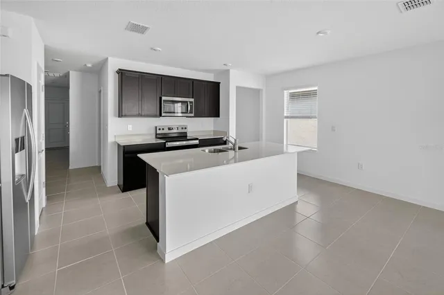 a kitchen with stainless steel appliances a stove top oven a sink a refrigerator white cabinets and wooden floor