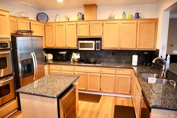 a kitchen with stainless steel appliances granite countertop a sink a stove and a refrigerator