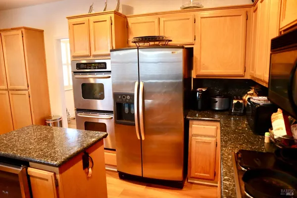 a view of a kitchen with an empty room and wooden floor